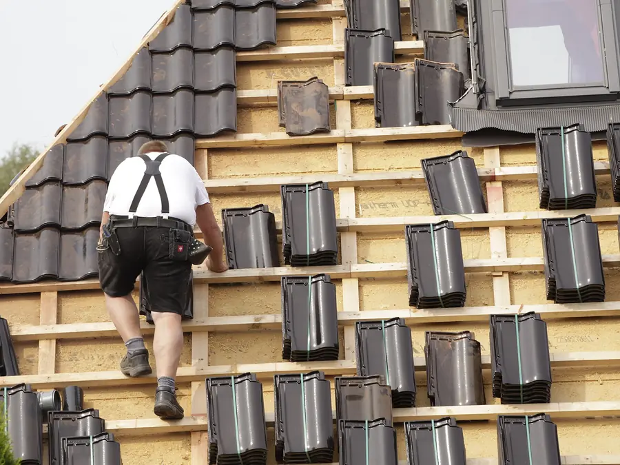 Dakdekker legt antraciet dakpannen op de panlatten, dakwerk in Amsterdam